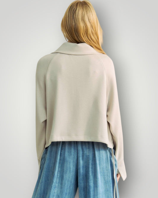 Person wearing a light-colored jacket and blue pants on a plain background