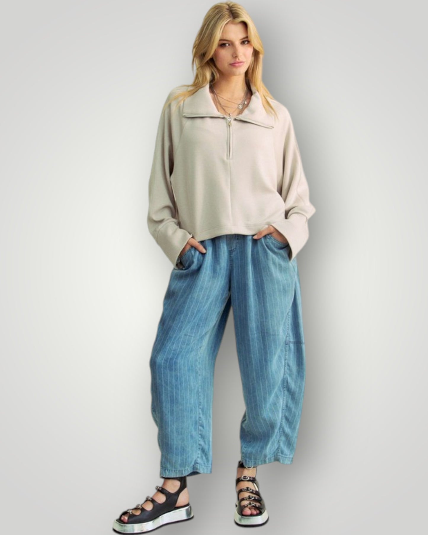 Woman wearing a beige jacket and blue jeans against a white background