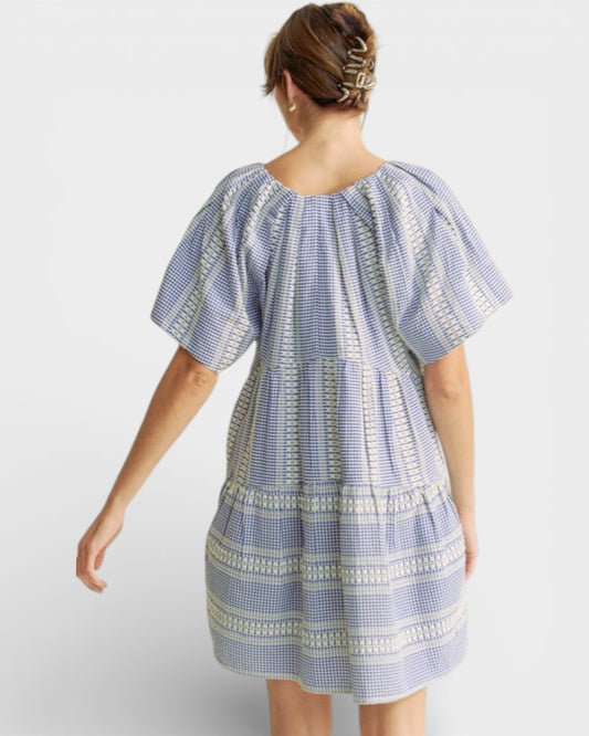 Woman wearing a blue and white patterned dress on a white background