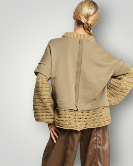 Person wearing a beige jacket with textured sleeves on a plain background