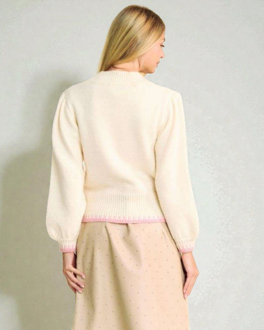 Woman wearing a light-colored cardigan and skirt against a plain background