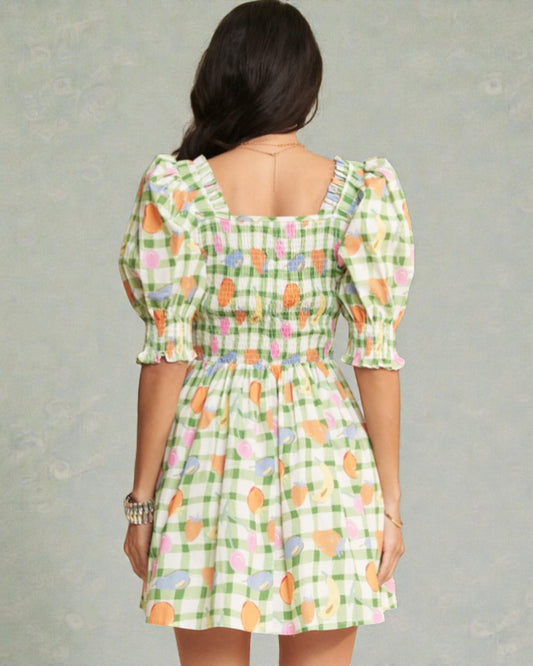 Woman wearing a green checkered dress with colorful patterns on a gray background