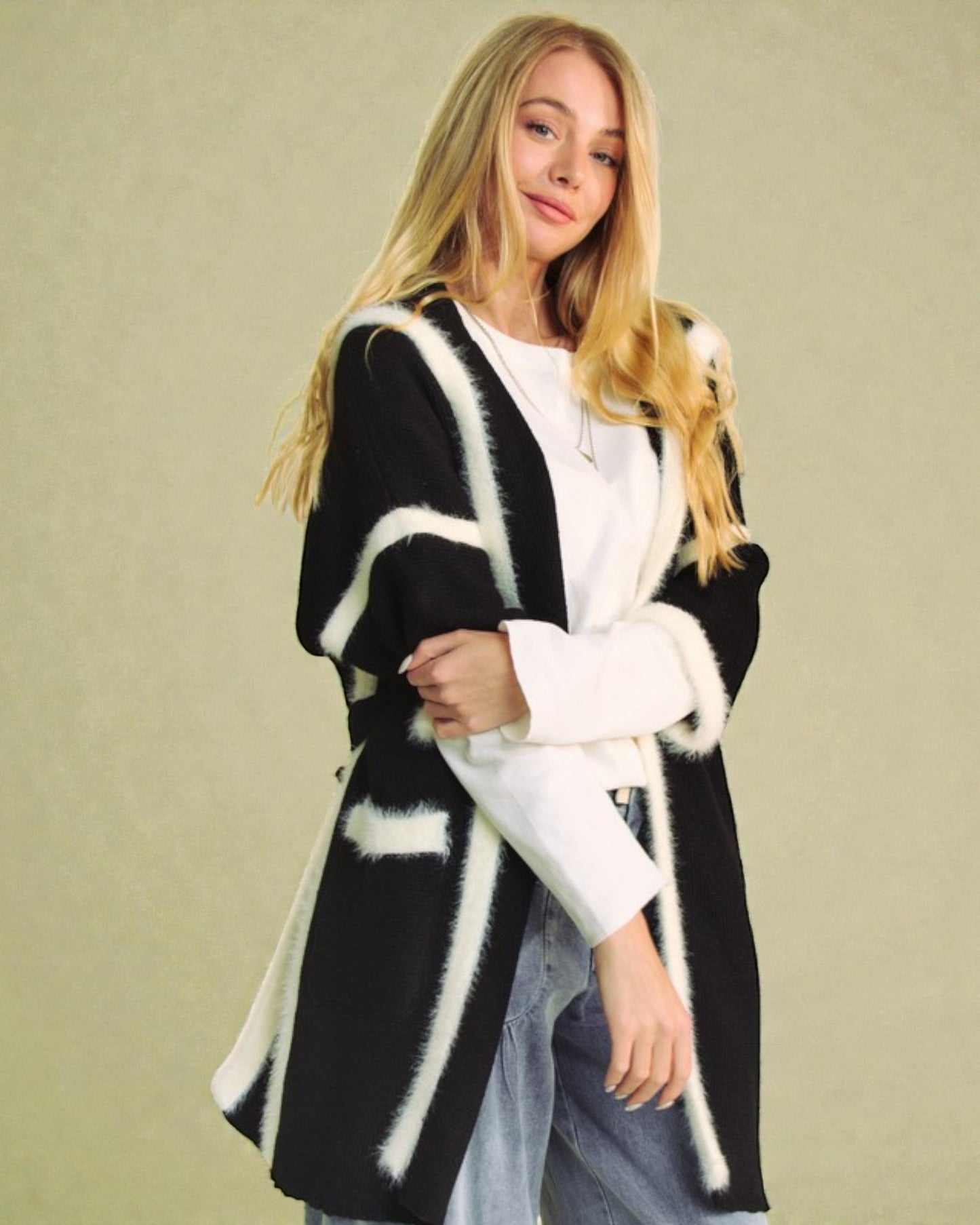 Woman wearing a black and white patterned cardigan against a beige background