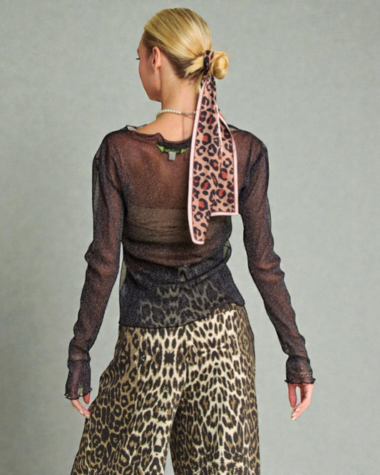 Person wearing a sheer brown top and leopard print pants with a matching scarf on a gray background