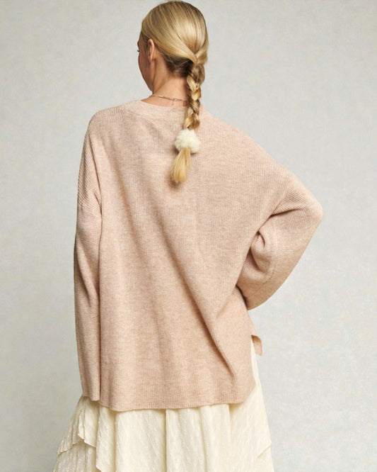 Person wearing a beige sweater with a plain background
