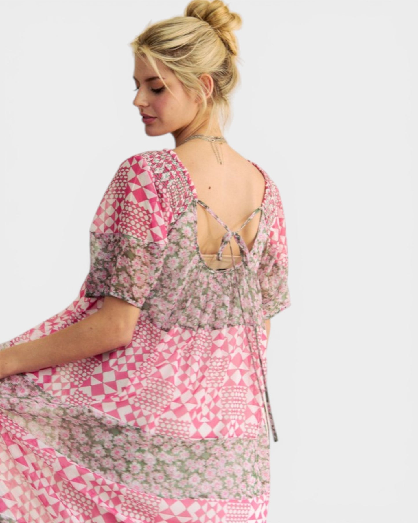 Woman wearing a pink and patterned dress on a white background