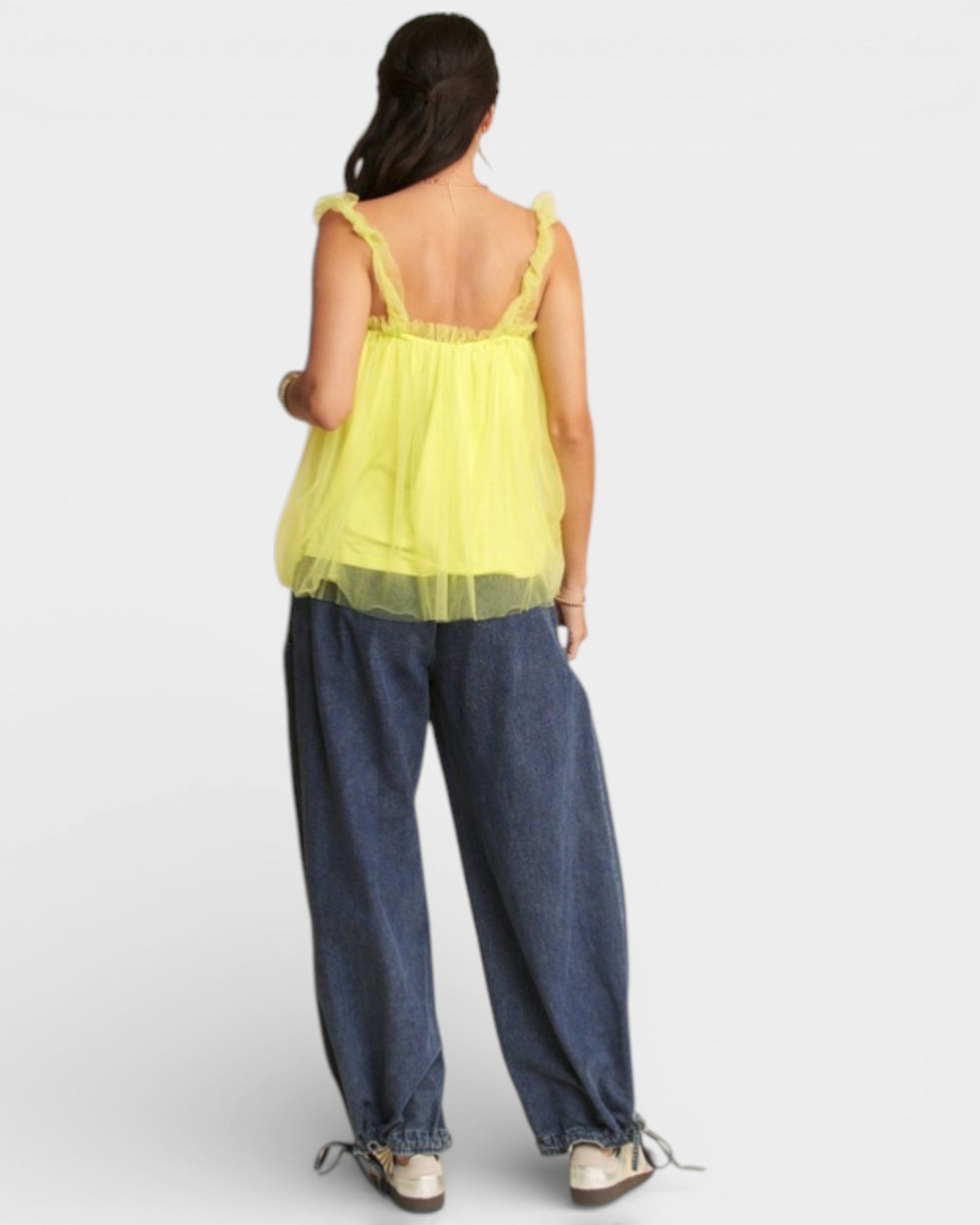Person wearing a yellow top and blue jeans on a white background