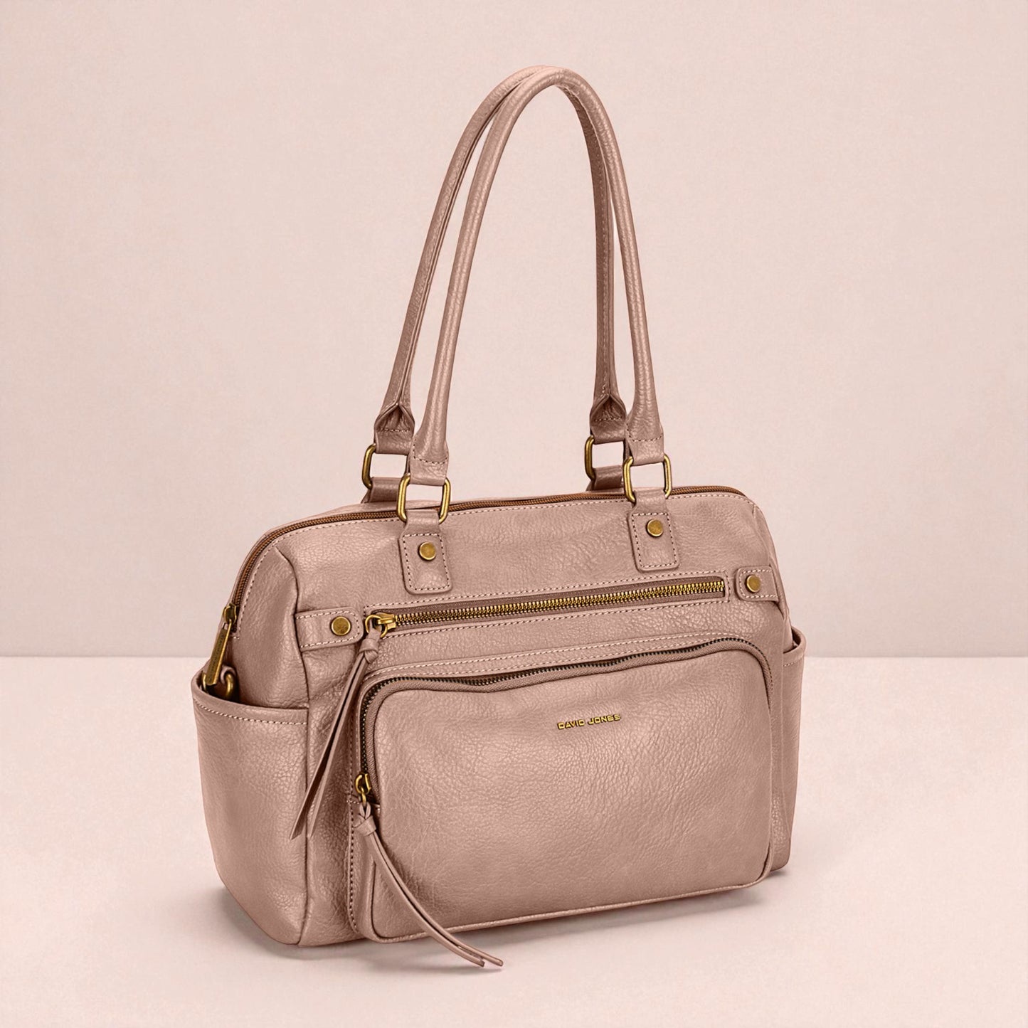 Pink handbag with gold zippers on a light pink background