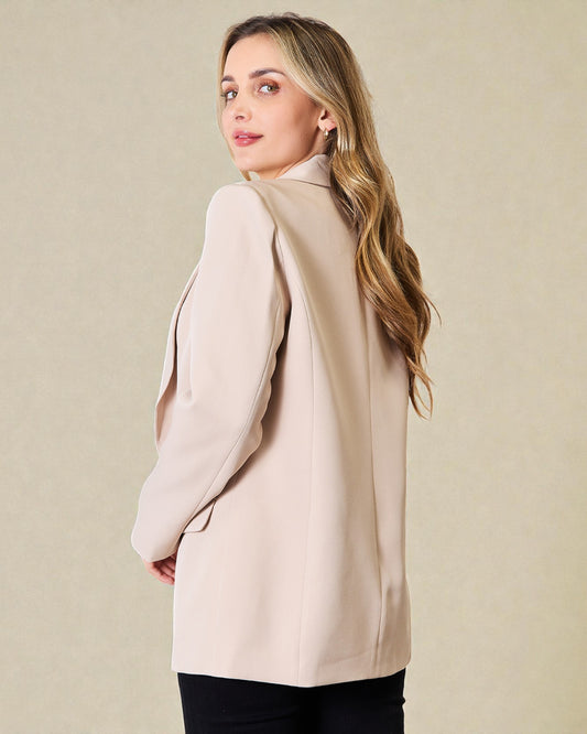 Woman wearing a beige blazer against a beige background