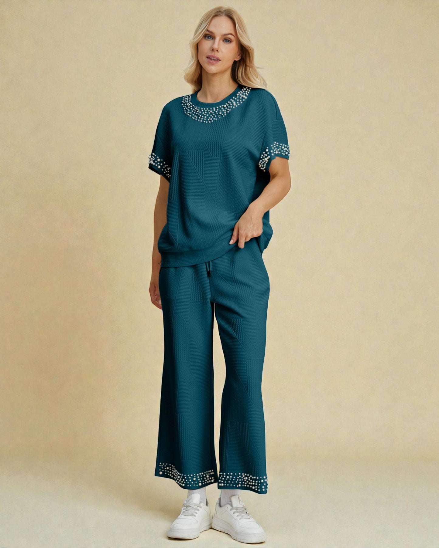 Woman wearing a teal outfit with embroidery on a beige background