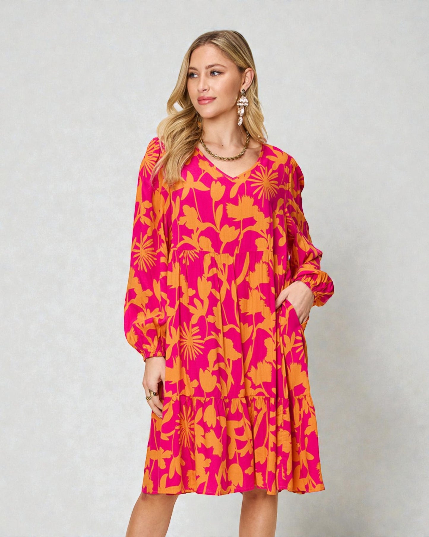 Woman wearing a bright pink and orange patterned dress on a plain background