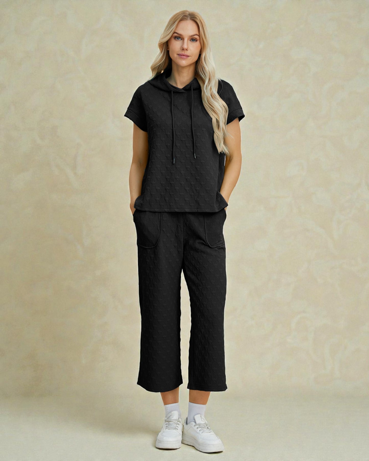 Woman wearing a black outfit with a beige background