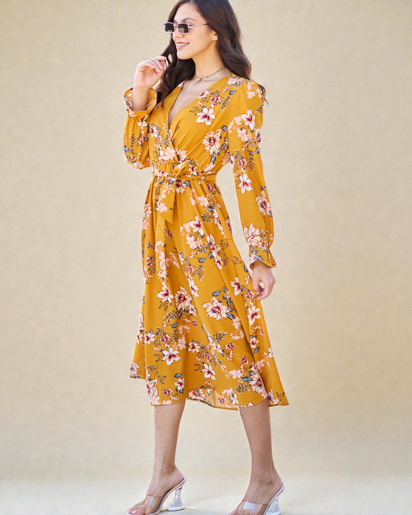 Woman wearing a yellow floral dress against a beige background