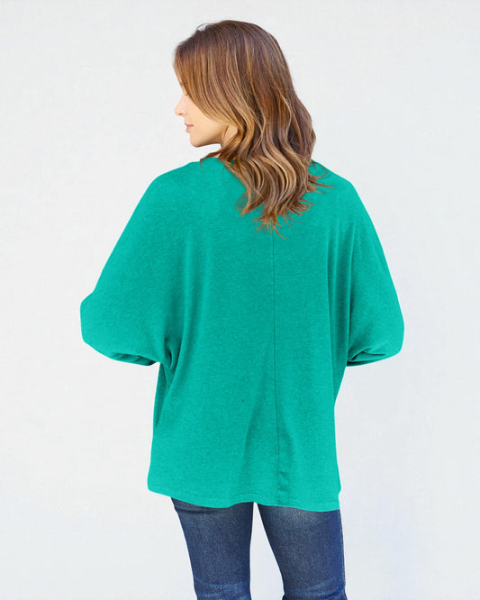 Person wearing a teal oversized shirt on a white background