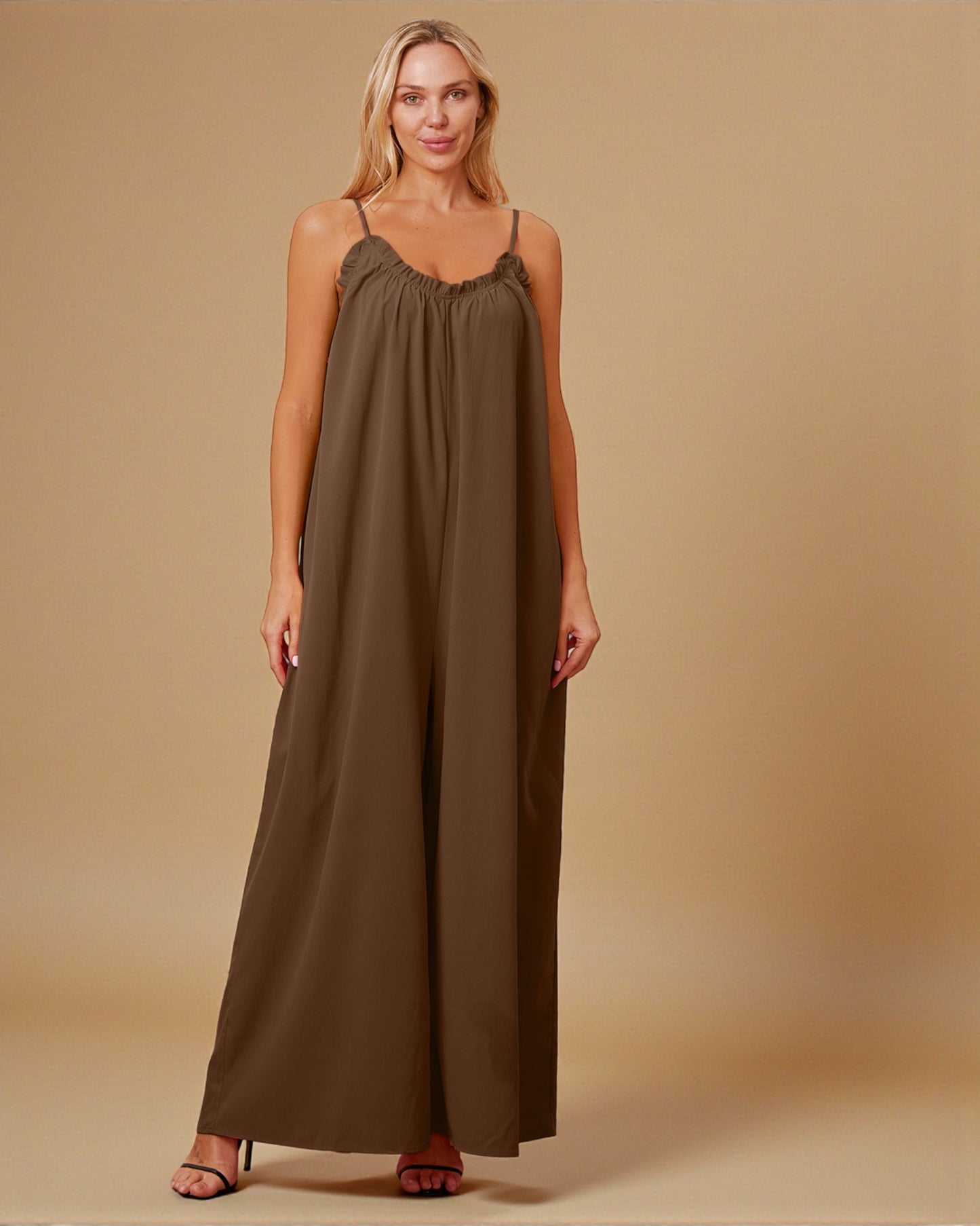 Woman wearing a brown jumpsuit against a beige background