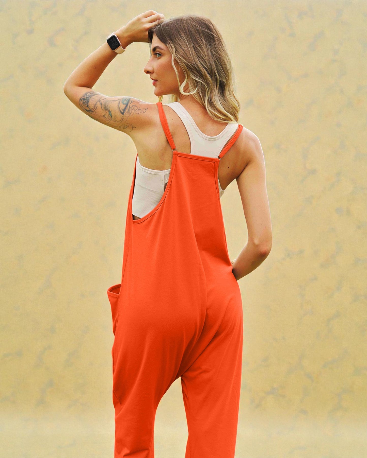 Woman wearing orange overalls against a beige background