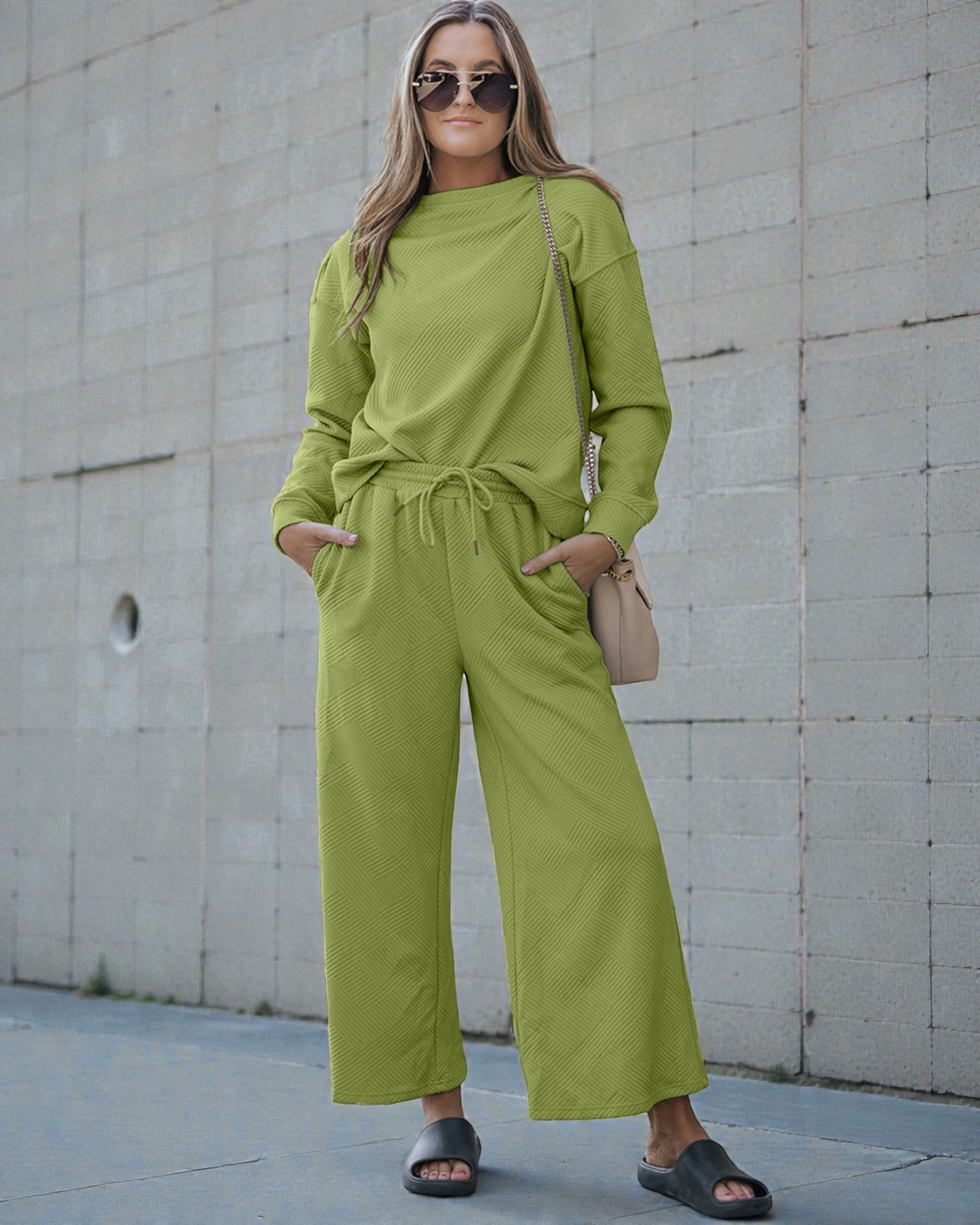 Woman wearing a green outfit standing against a concrete wall.