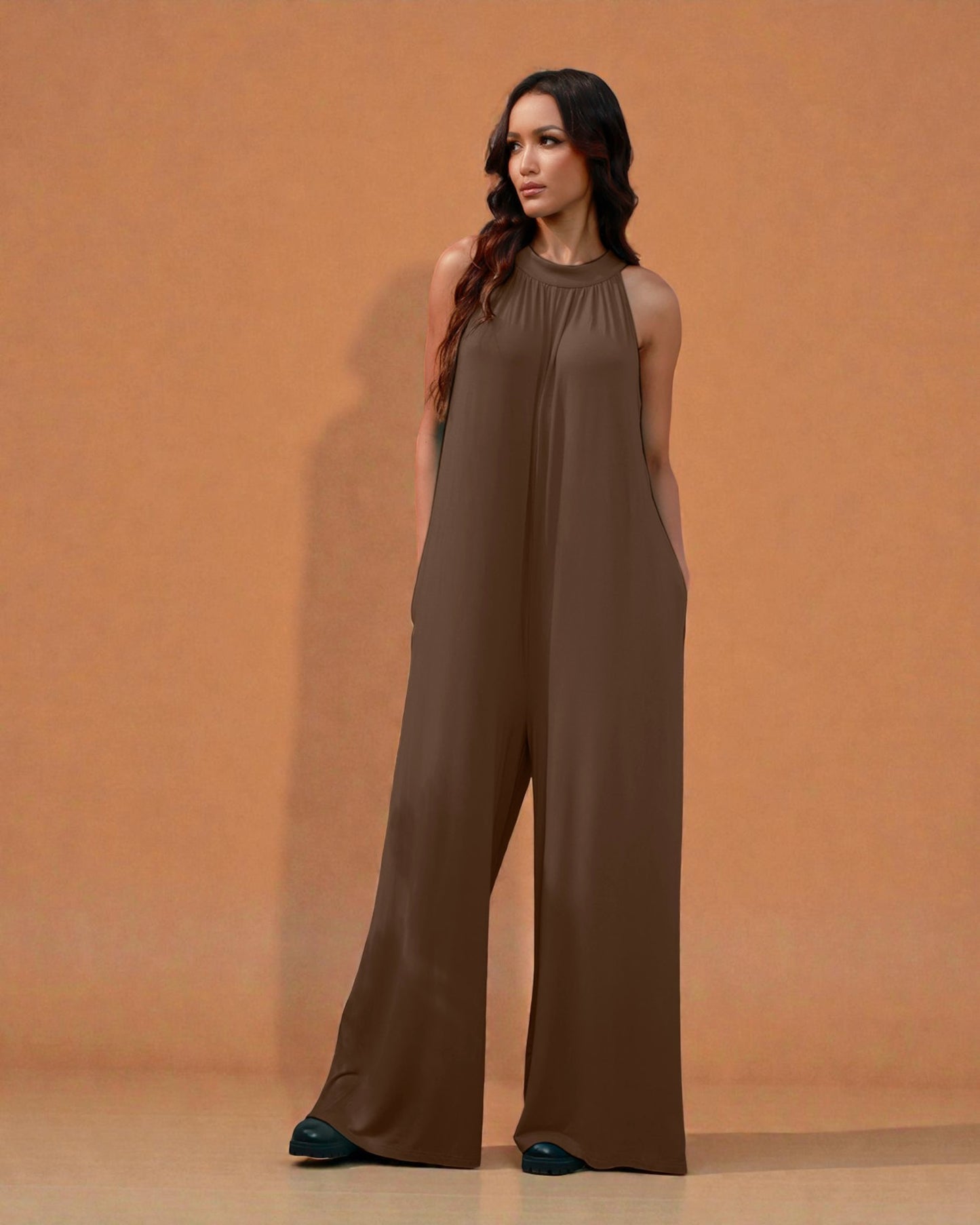 Woman wearing a brown jumpsuit against an orange background