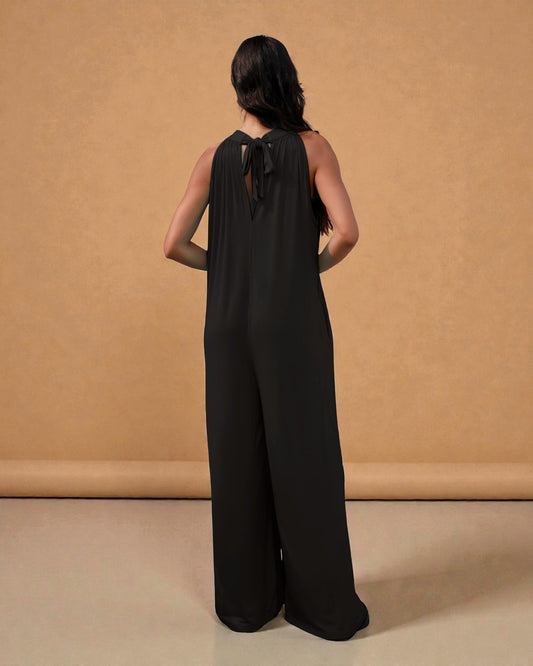 Woman wearing a black jumpsuit against a beige background