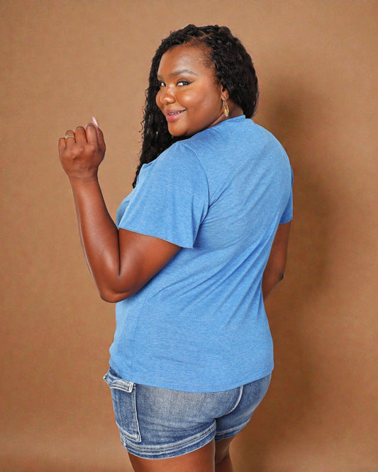 Woman wearing a blue t-shirt and denim shorts against a brown background
