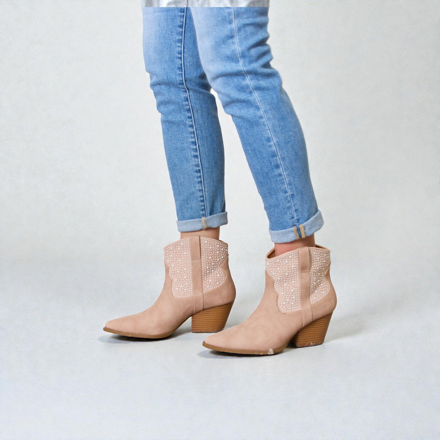 Beige ankle boots with wooden heel and light blue jeans on a white background