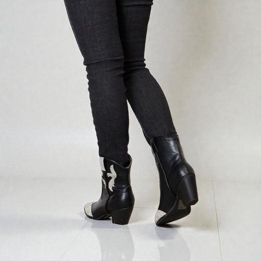 Black wedge boots worn with black pants on a white background