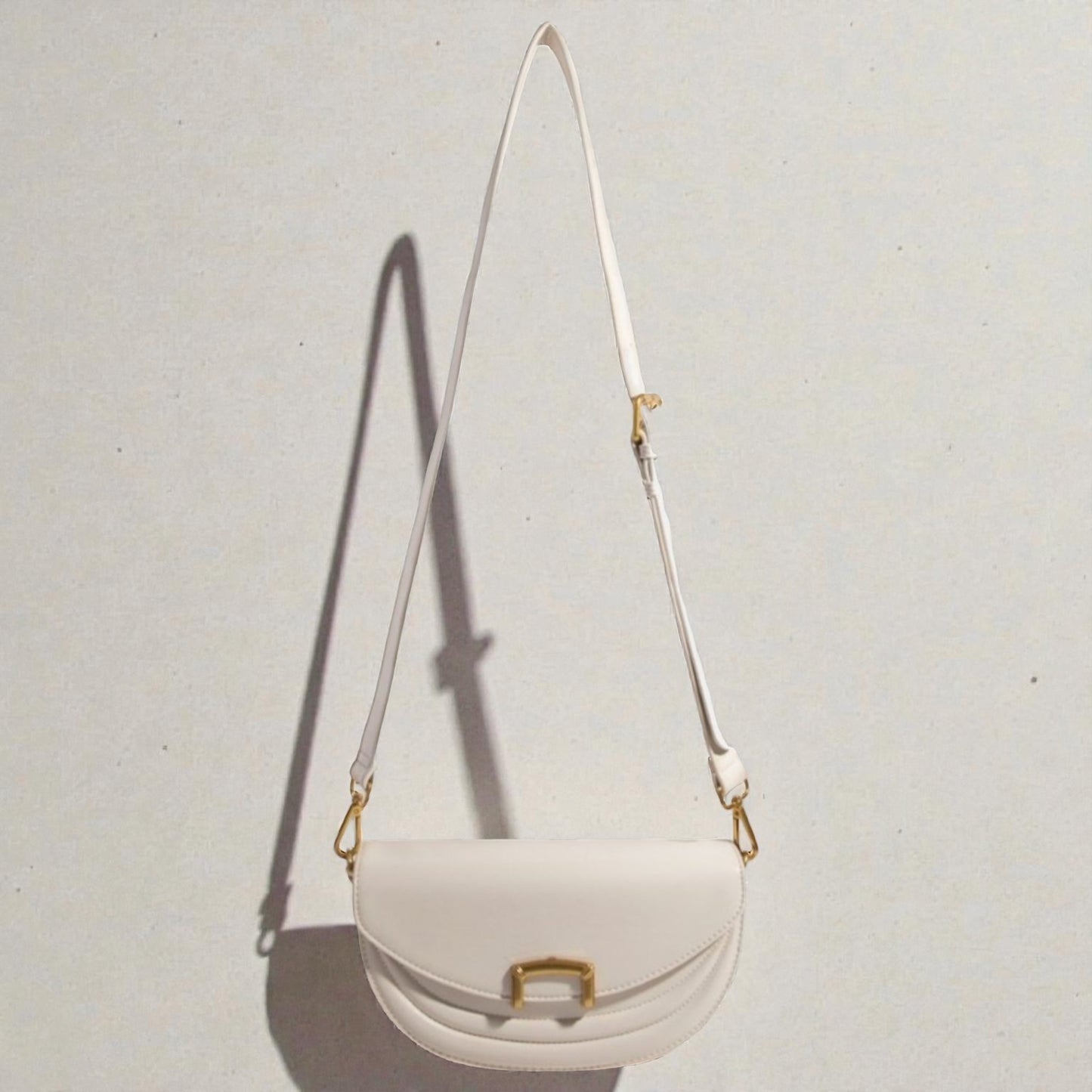 White handbag with gold accents on a light gray background