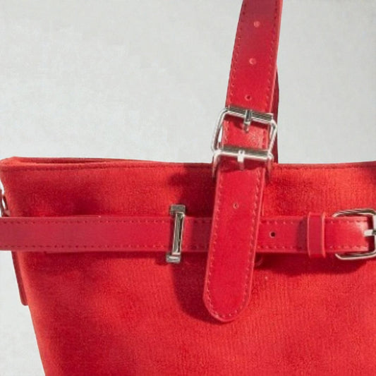 Red handbag with silver buckles on a light gray background