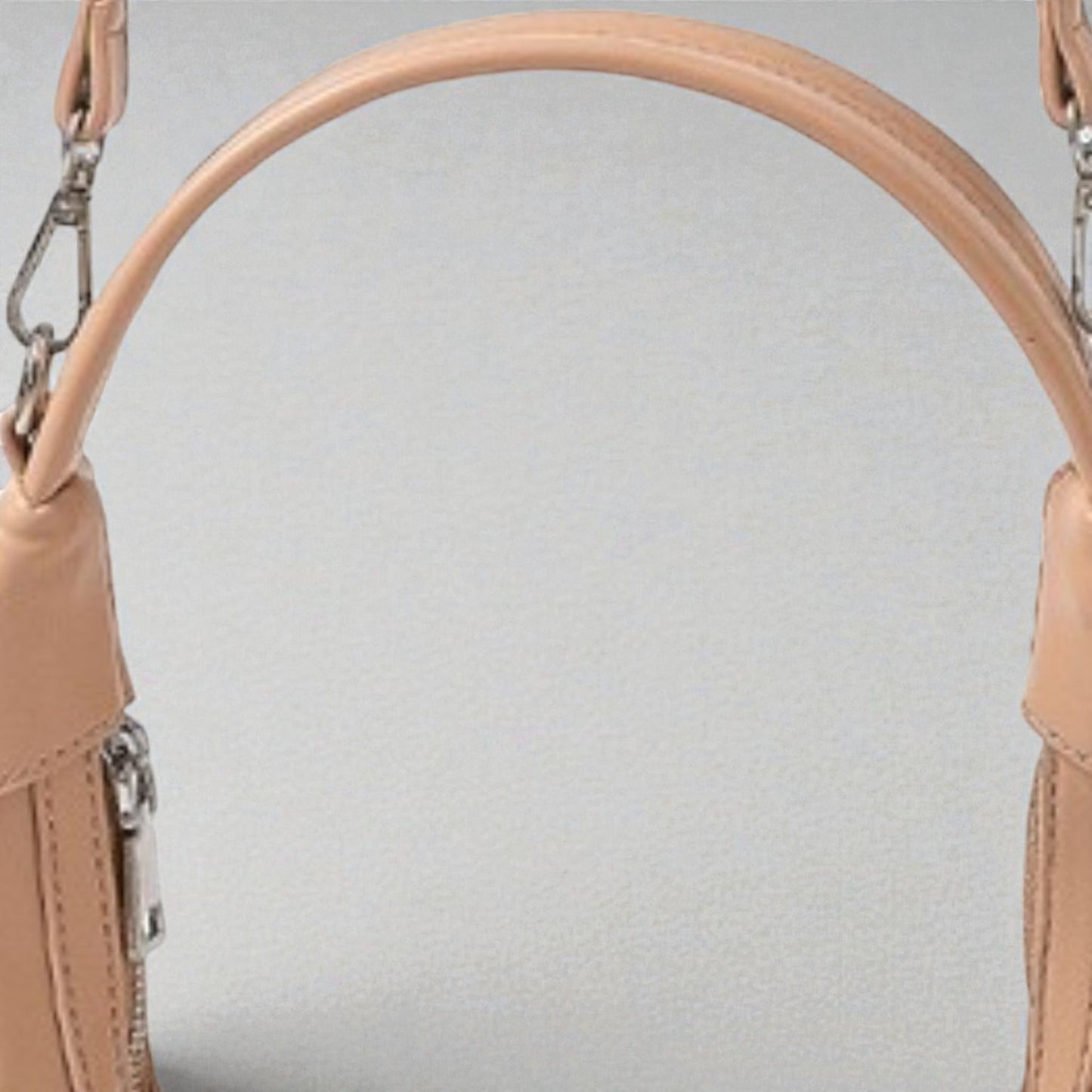 Close-up of a beige handbag with a handle on a light gray background