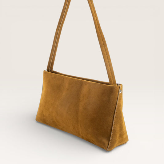 Brown leather handbag with a strap on a light gray background