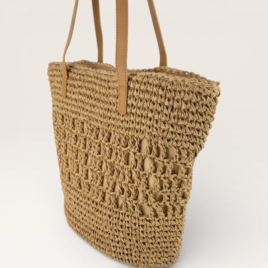 Woven straw bag with brown handles on a white background