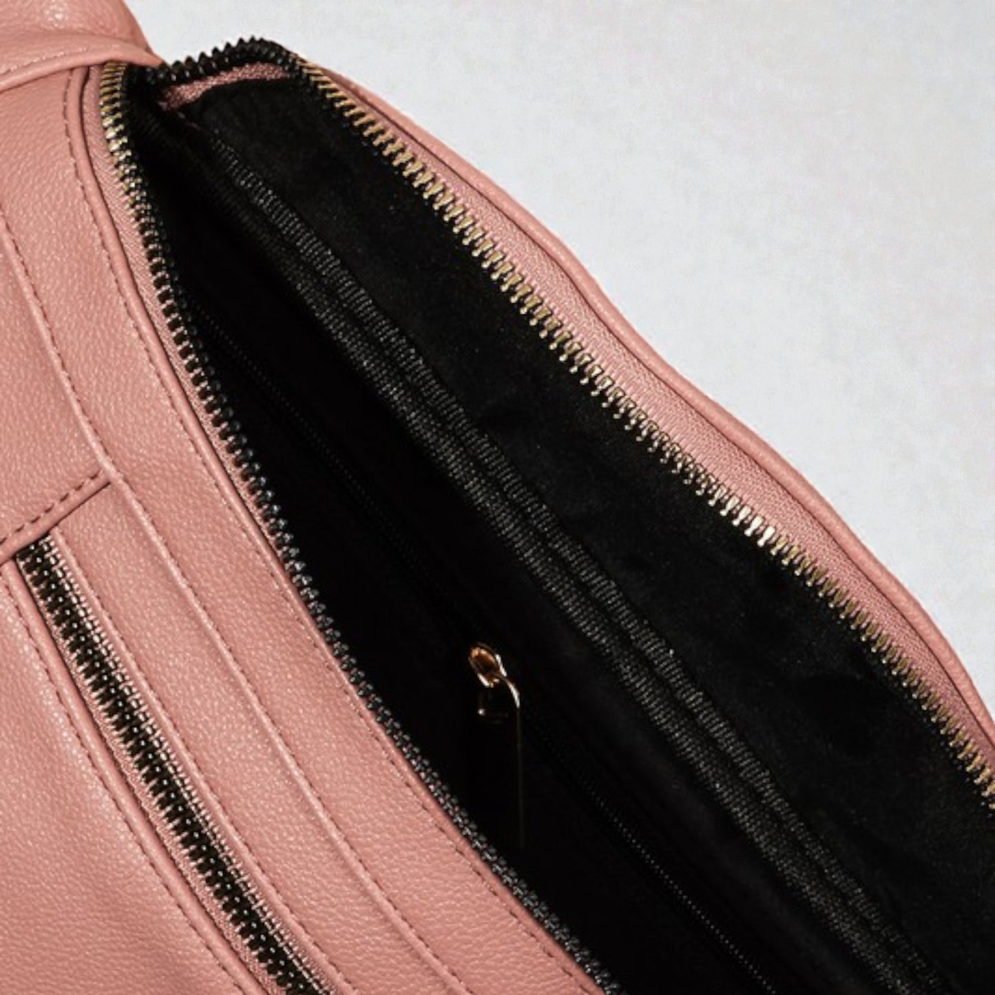 Close-up of a pink leather bag with a zipper on a light gray background
