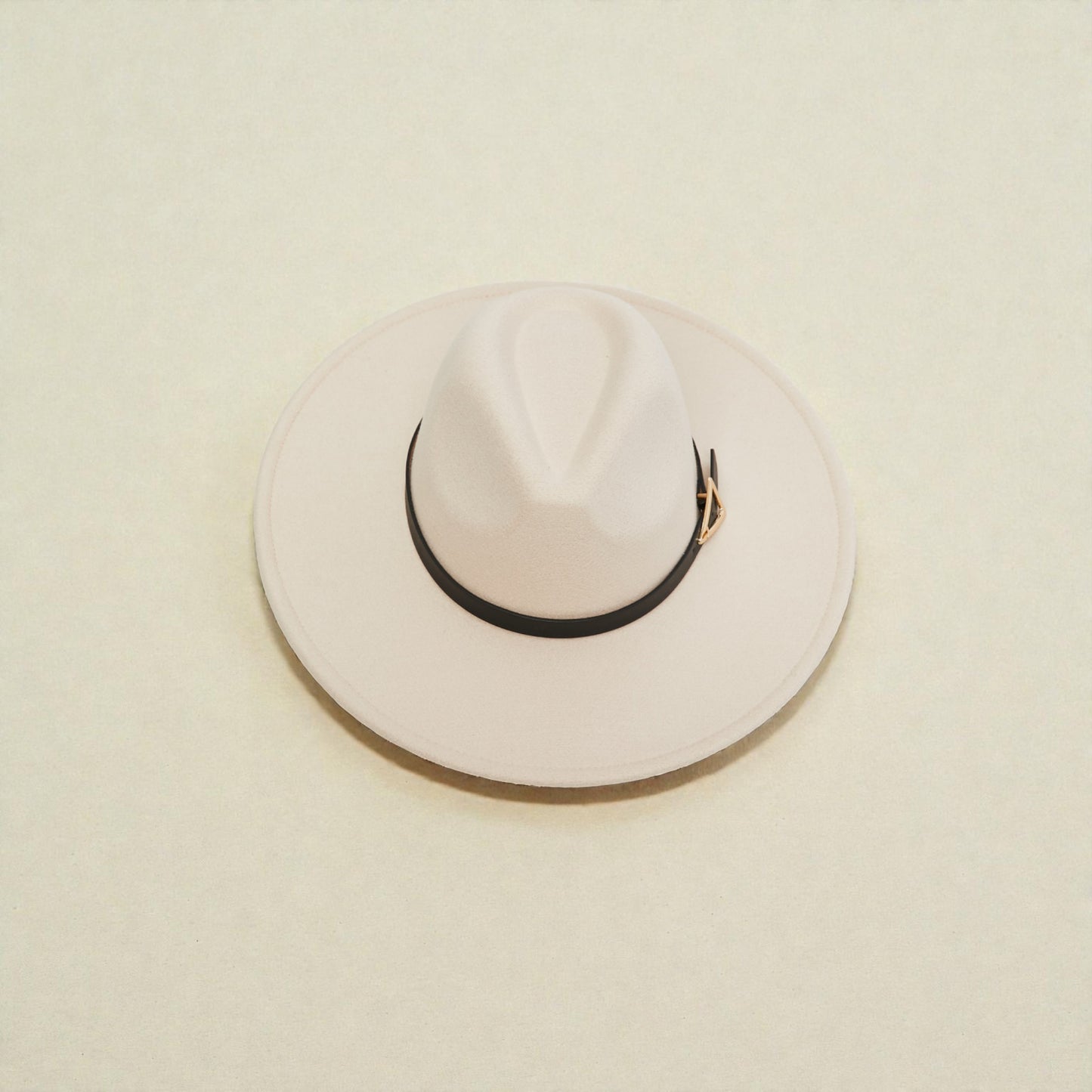 White fedora hat with a black band on a beige background