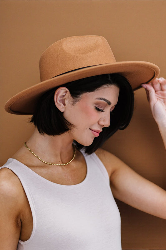 Woman wearing a brown hat against a brown background