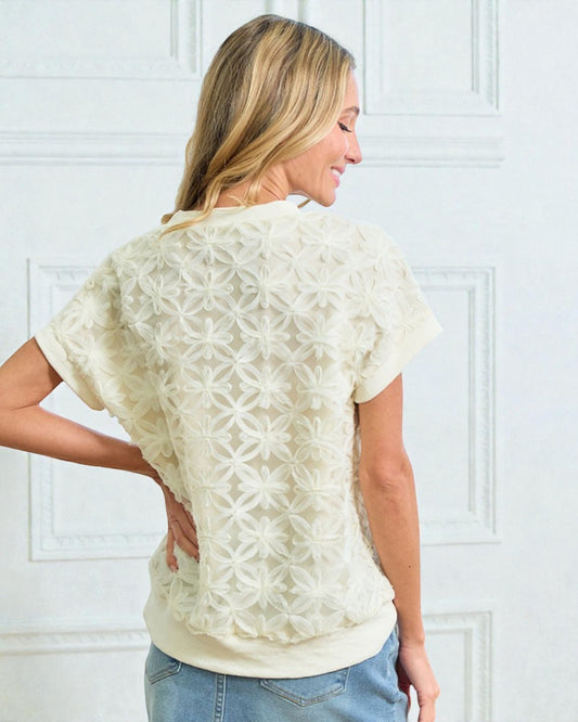 Woman wearing a cream-colored lace top against a white background