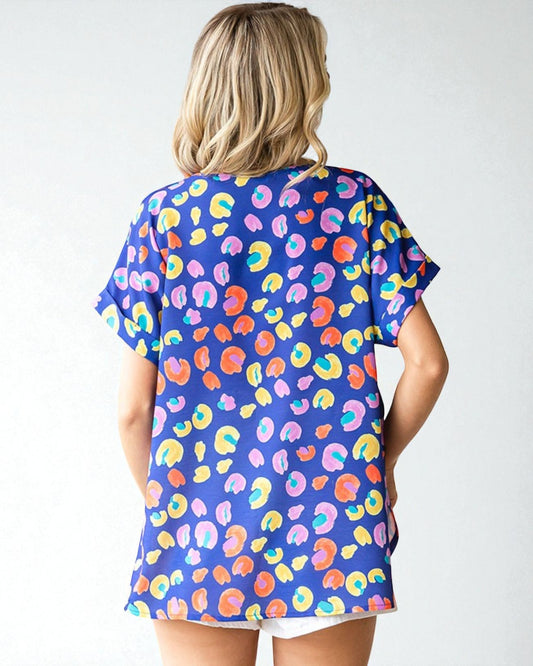 Woman wearing a colorful patterned shirt with a plain background