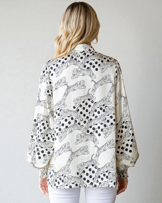 Woman wearing a patterned blouse with tigers and polka dots on a plain background