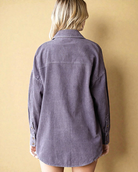 Person wearing a purple shirt against a beige wall