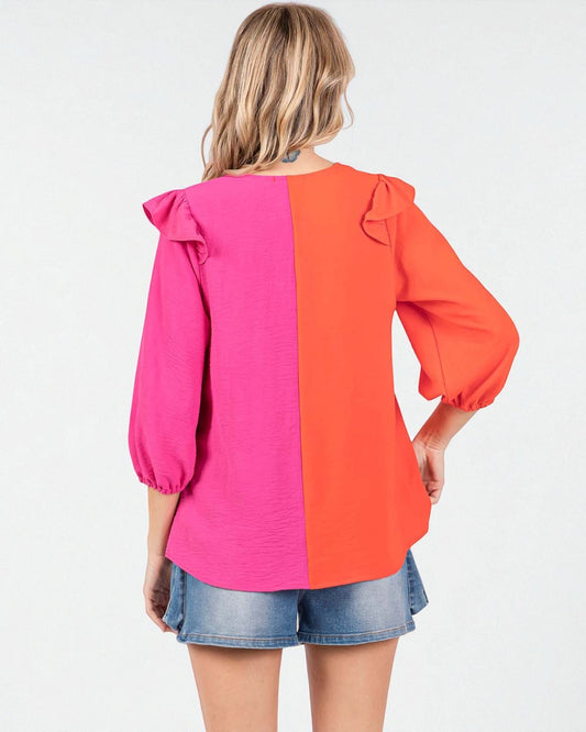 Woman wearing a pink and orange blouse with ruffled sleeves on a white background