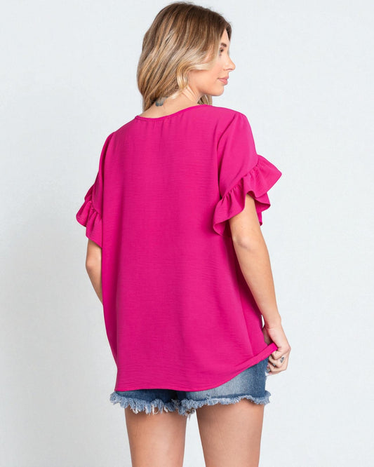 Woman wearing a bright pink blouse with ruffled sleeves on a white background