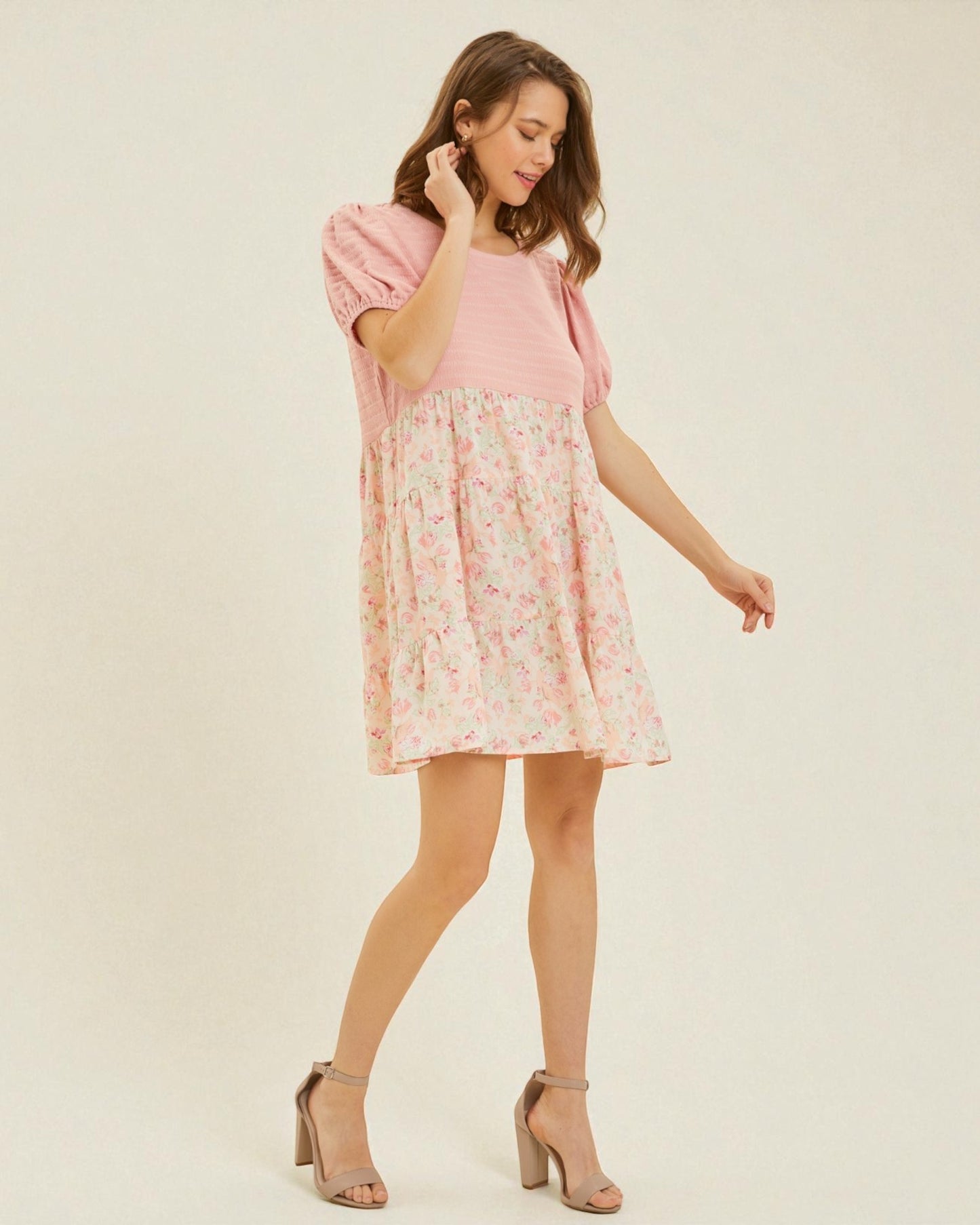 Woman wearing a pink dress with floral pattern on a beige background