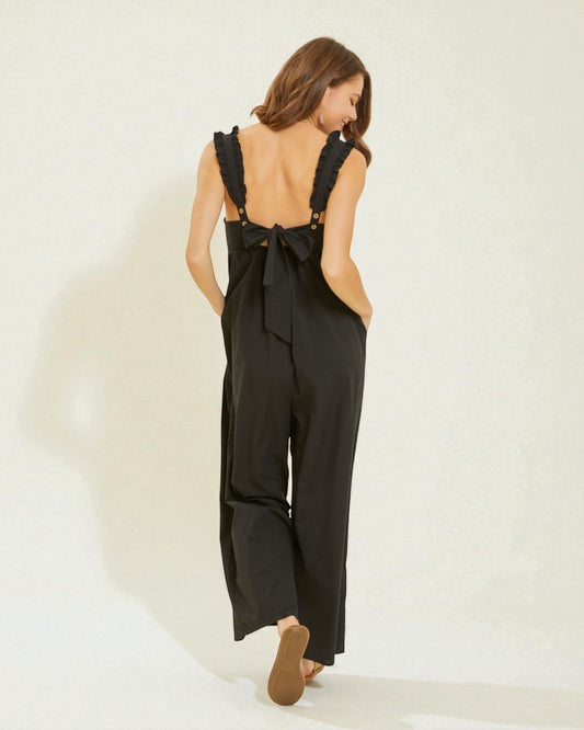 Woman wearing a black jumpsuit with open back on a white background