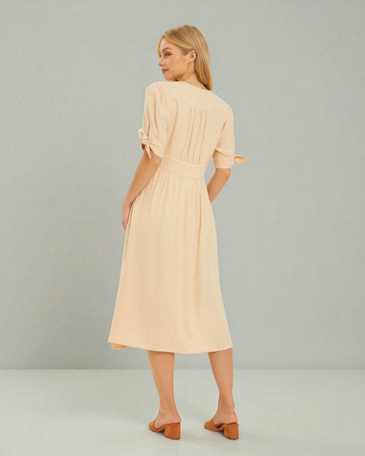 Woman wearing a beige dress against a plain background