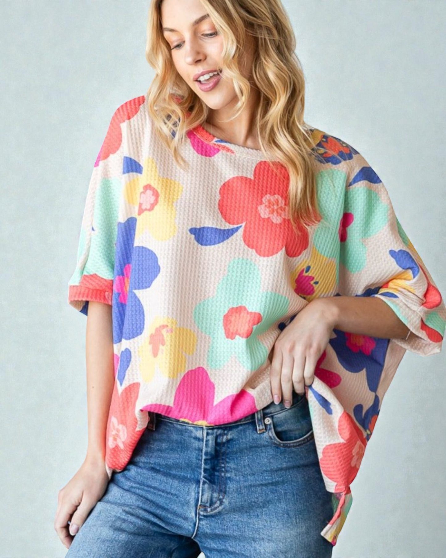Woman wearing a colorful floral sweater against a plain background