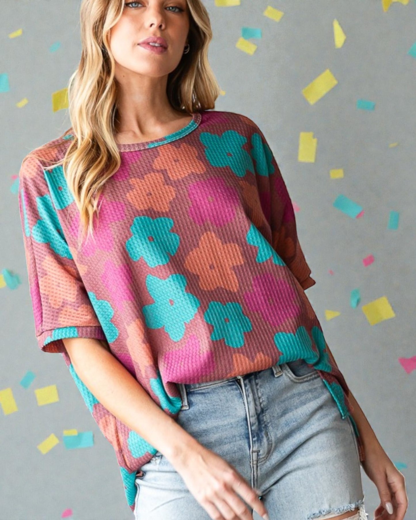 Woman wearing a colorful patterned sweater with a gray background and confetti