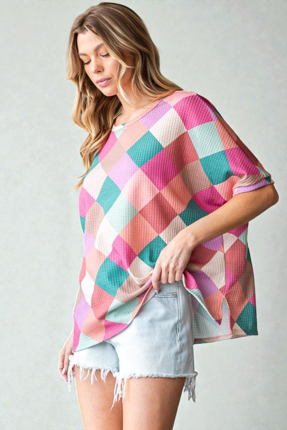 Woman wearing a colorful checkered poncho against a plain background