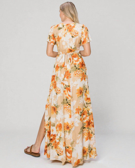 Woman wearing a floral dress with orange flowers on a plain background
