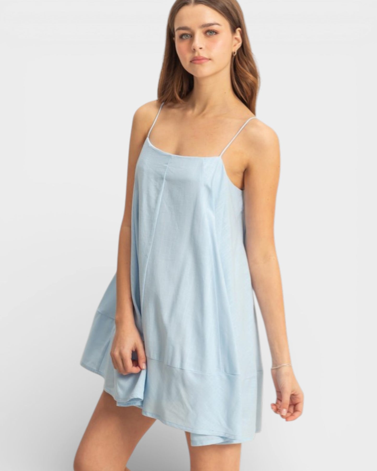 Woman wearing a light blue slip dress on a white background