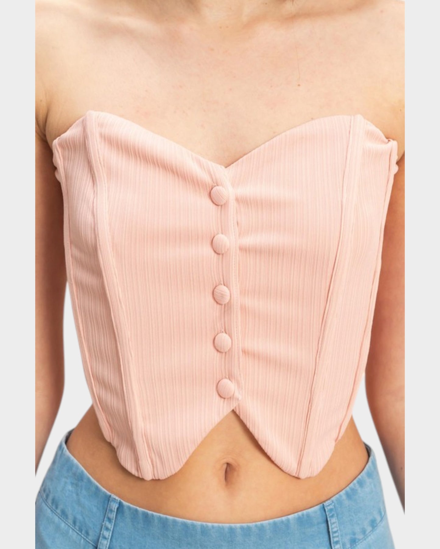 Pink ribbed corset top worn by a person with a white background