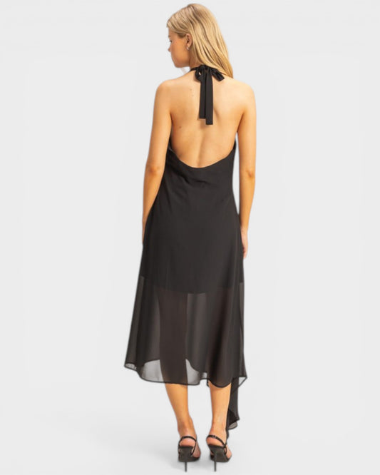 Woman wearing a black halter neck dress with sheer panels on a white background